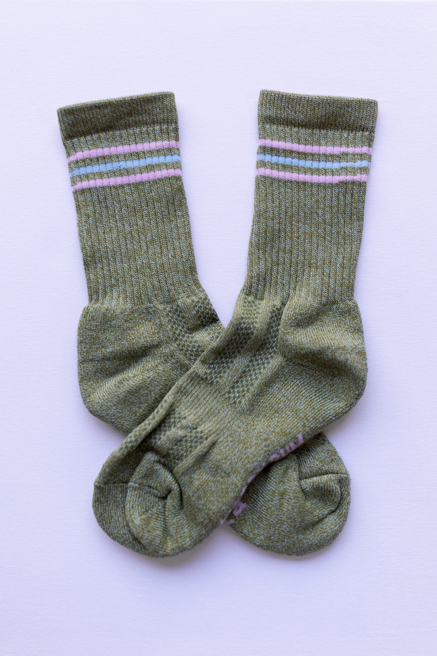 Pair of green socks with pink stripes on a light purple background

