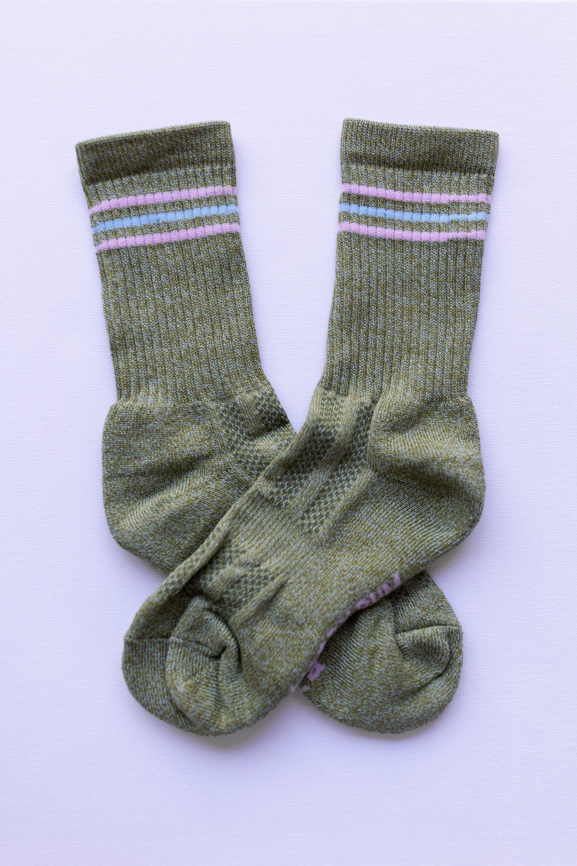 Pair of green socks with pink stripes on a light purple background

