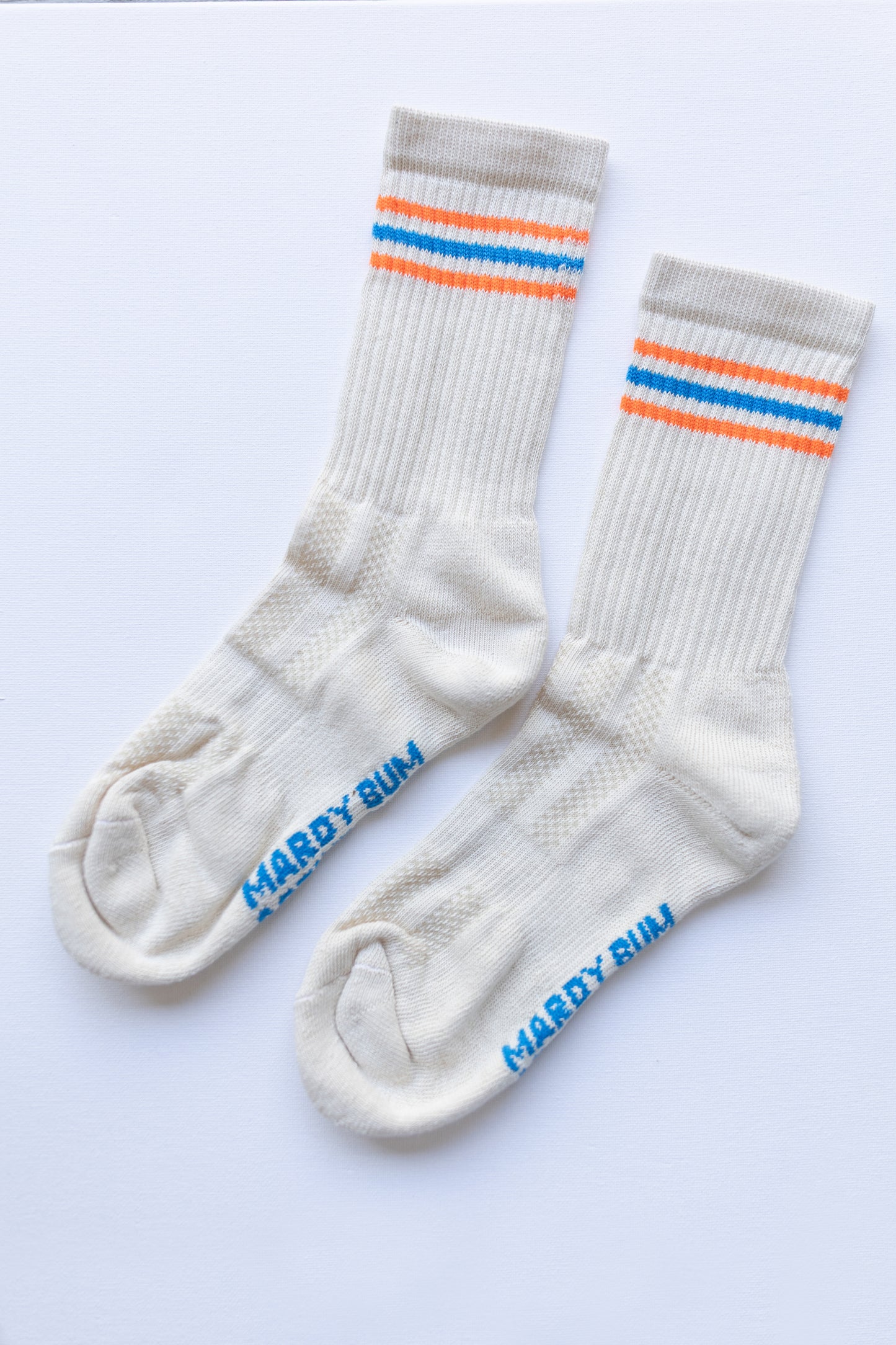 White socks with blue and orange stripes and 'Mardy bum active club" branding on sole 

